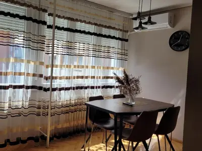 a dining room with a table and chairs and a window at Duka Apartment in Niš
