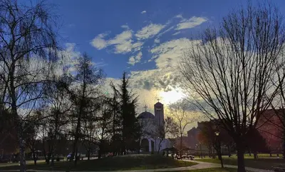a building with a clock tower in a park with trees at Duka Apartment in Niš