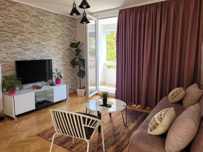 a living room with a couch and a tv at Duka Apartment in Niš