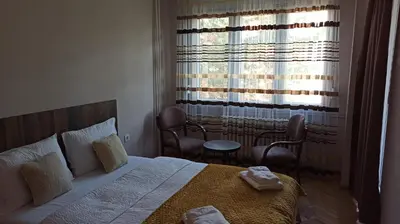 a bedroom with a bed and chairs and a window at Duka Apartment in Niš