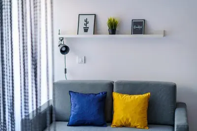 a gray couch with two blue and yellow pillows at Apartments Karamarković 1 in Vrnjačka Banja