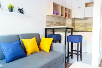 a living room with a couch with yellow and blue pillows at Apartments Karamarković 1 in Vrnjačka Banja