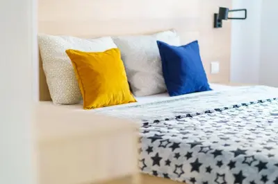 a bed with blue and yellow pillows on it at Apartments Karamarković 1 in Vrnjačka Banja