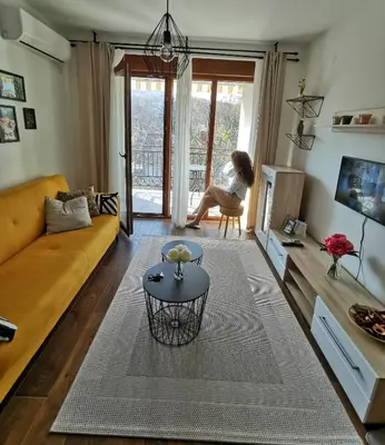 a woman sitting in a chair in a living room at Sunset Vrnjačka Banja in Vrnjačka Banja