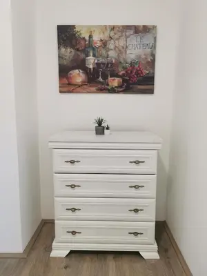 a white dresser with a painting on the wall at Apartman Centar in Aleksandrovac