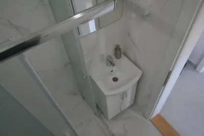 a white bathroom with a sink and a mirror at Apartment 13 in Vrnjačka Banja