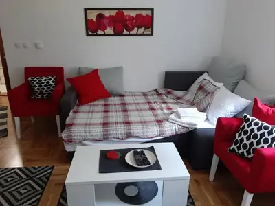a living room with a bed and red chairs at Apartman OAZA in Vrnjačka Banja