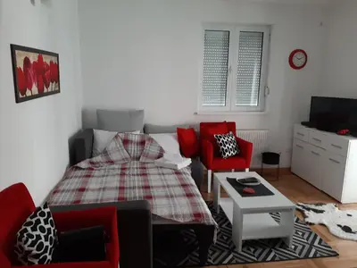 a living room with a bed and red chairs at Apartman OAZA in Vrnjačka Banja