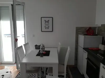 a kitchen with a white table with chairs and a white refrigerator at Apartman OAZA in Vrnjačka Banja