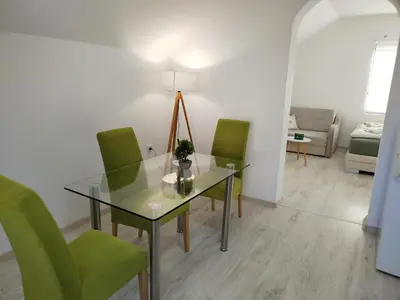 a dining room with a glass table and green chairs at Studio Andrijana Sokobanja in Soko Banja