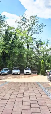 two cars parked in a parking lot with trees at Apartman Ana in Vrnjačka Banja