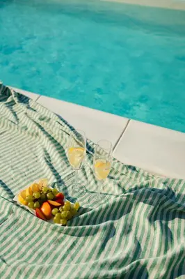 a plate of grapes and wine glasses next to a pool at House Milovanovic in Soko Banja