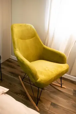 a yellow chair sitting next to a bed at Apartmani Jović in Kuršumlija