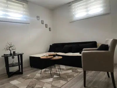 a living room with a black couch and a chair at Apartman Urosevic in Jagodina