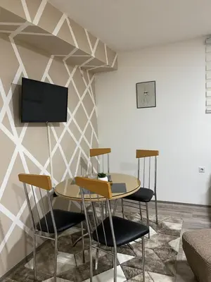 a room with a table and chairs and a tv on a wall at Apartman Urosevic in Jagodina