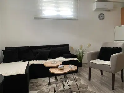 a living room with a black couch and two chairs at Apartman Urosevic in Jagodina