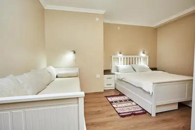 a white bedroom with two beds and a couch at AquaLux in Soko Banja