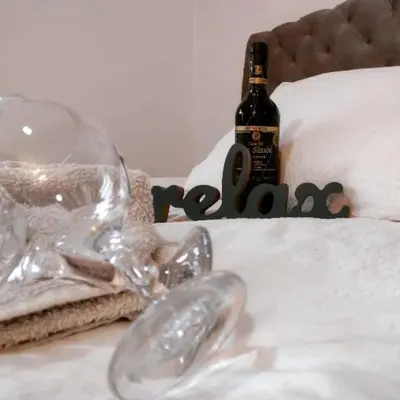 a bottle of wine sitting on top of a bed at Smestaj Stanisavljevic in Soko Banja