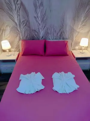 a pink bed with two white pillows and two tables at Smestaj Stanisavljevic in Soko Banja