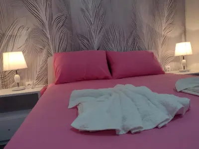 a bed with pink and white sheets and pillows at Smestaj Stanisavljevic in Soko Banja