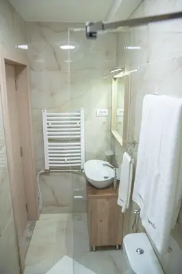 a white bathroom with a sink and a mirror at Mehana apartmani in Leskovac