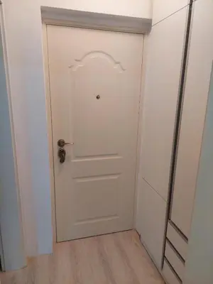 a white door in a room with a wooden floor at Vrnjacki apartmani in Vrnjačka Banja