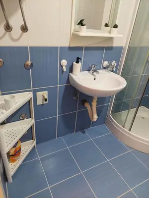 a blue tiled bathroom with a sink and a shower at Vrnjacki apartmani in Vrnjačka Banja