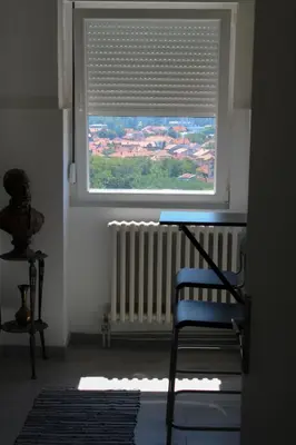 a window with a radiator and a blue chair in a room at Bianco nero appartamento in Niš