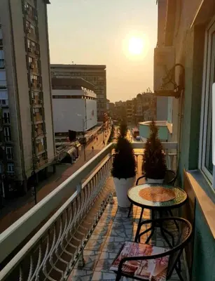 a balcony with two tables and a view of a city at Savić Apartment CENTER - PARKING FREE in Niš