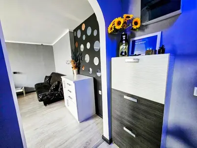 a living room with a white dresser and a blue wall at Savić Apartment CENTER - PARKING FREE in Niš