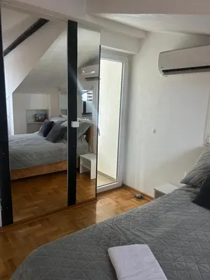 a bedroom with two beds and a large mirror at MM Apartman in Kruševac