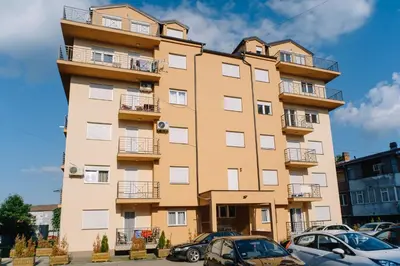 a tall building with cars parked in front of it at Apartman Ristić in Vrnjačka Banja