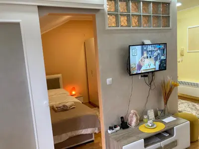 a small room with a bed and a tv on the wall at Apartmani Grand LUX in Vrnjačka Banja