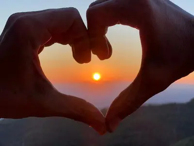 a pair of hands making a heart with the sunset in the background at Milmari M12 in Kopaonik