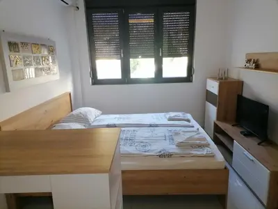a bedroom with a bed and a desk and a television at Stojanović Apartments in Niš