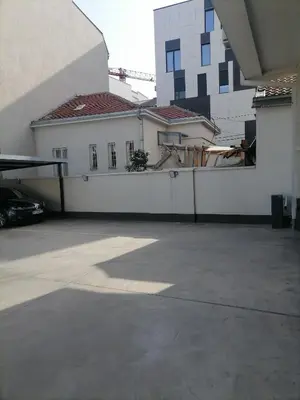 a parking lot with a white fence and a house at Stojanović Apartments in Niš