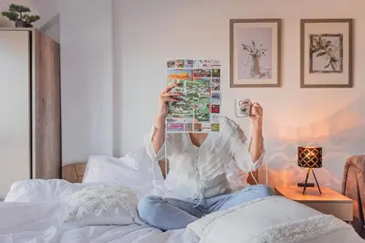 a person sitting on a bed reading a magazine at Cicmilovic P63, Milmari Resort, Kopaonik in Kopaonik