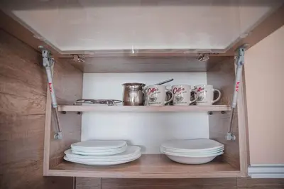 a pantry with plates and cups on a shelf at Cicmilovic P63, Milmari Resort, Kopaonik in Kopaonik