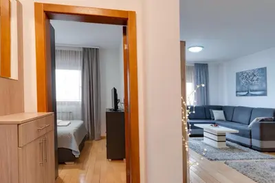 a living room with a blue couch and a bed at Apartman Nada de lux in Vrnjačka Banja