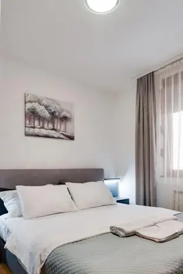 a bedroom with a large bed with white sheets at Apartman Nada de lux in Vrnjačka Banja