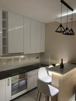 a kitchen with white cabinets and a table and chairs at Palas Central in Niš