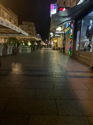 an empty street at night with shops and restaurants at Palas Central in Niš