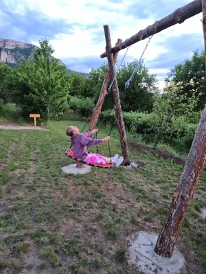 a little girl sitting on a swing in a field at Ramonda Serbica- Peaceful Retreat in Sicevo Gorge in Niš