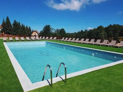 a large swimming pool with chairs on a grass field at Apartman IRINA 1243 in Kopaonik