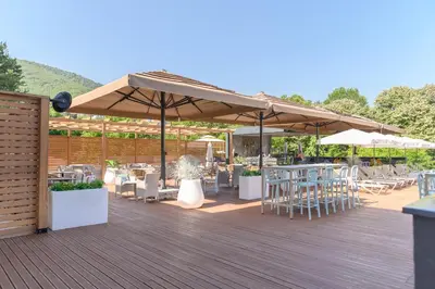 a wooden deck with tables and chairs and umbrellas at Hotel Sunce in Soko Banja