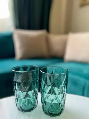 two green glass vases sitting on a table at Dis apartman 2 in Kruševac