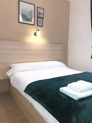 a bedroom with a white bed with a green blanket at Dis apartman 2 in Kruševac