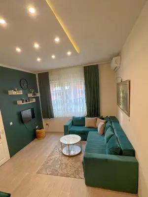a living room with a green couch and a table at Dis apartman 2 in Kruševac