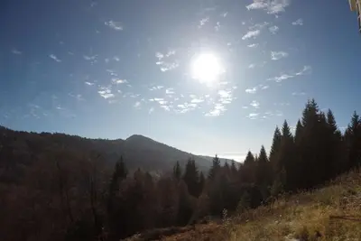 a sun in the sky over a mountain with trees at Apartman Nota in Kopaonik