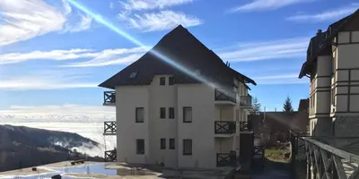 a building with a black roof on top of a mountain at Apartman Nota in Kopaonik